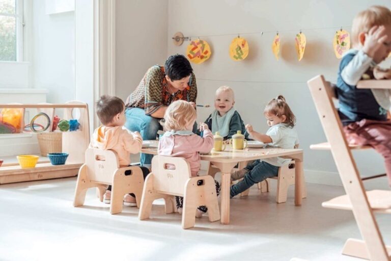 Liggend KDV Kleine groep kinderen eet aan lage tafel met PM